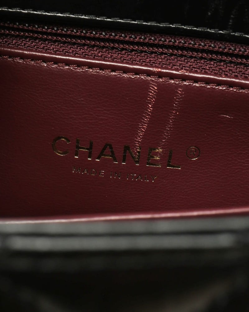 Interior close-up of a Chanel Small Coco Handle Bag displaying the gold 'Made in Italy' brand stamp on the burgundy lining.
