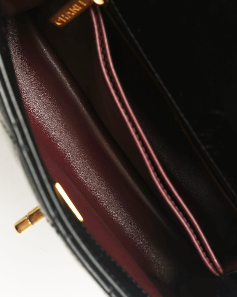 Interior close-up of a Chanel Small Coco Handle Bag, revealing the burgundy leather lining and gold logo stamp.