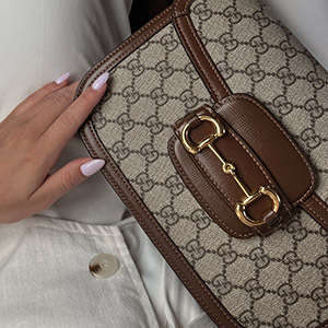 Louis Vuitton bag with a lot of charms held by a hand