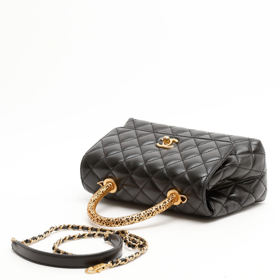 High-angle view of a Chanel Small Coco Handle bag in black leather with its patterned gold-tone top handle.
