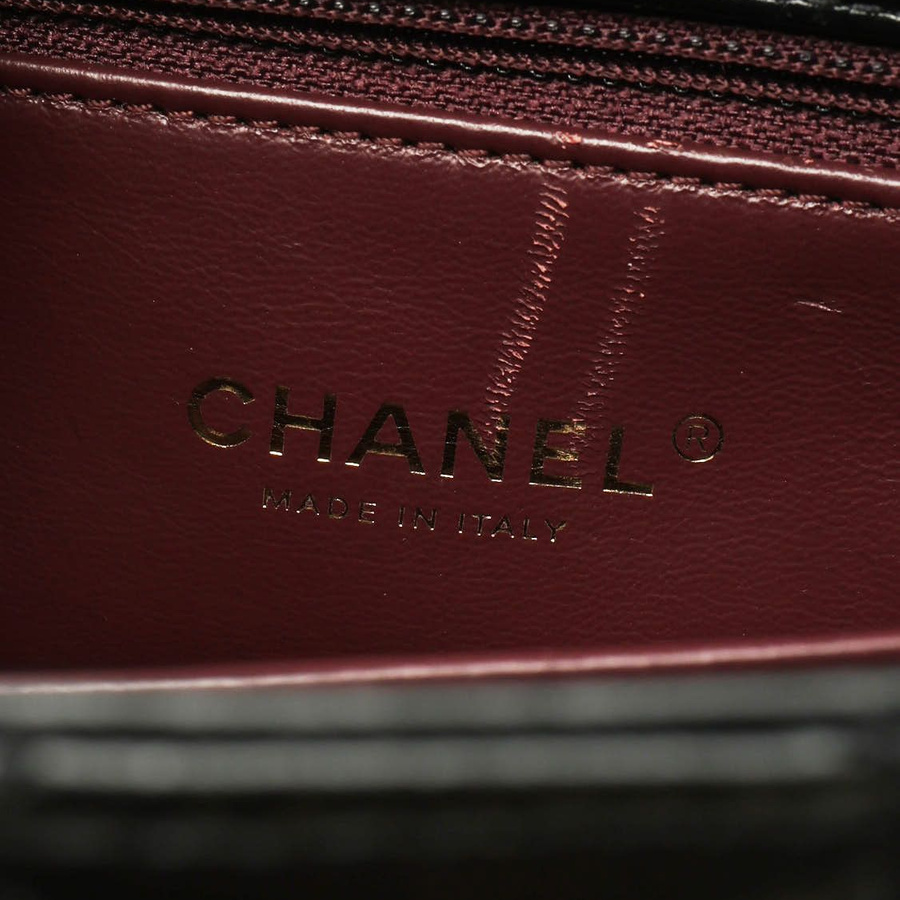 Interior close-up of a Chanel Small Coco Handle Bag displaying the gold 'Made in Italy' brand stamp on the burgundy lining.