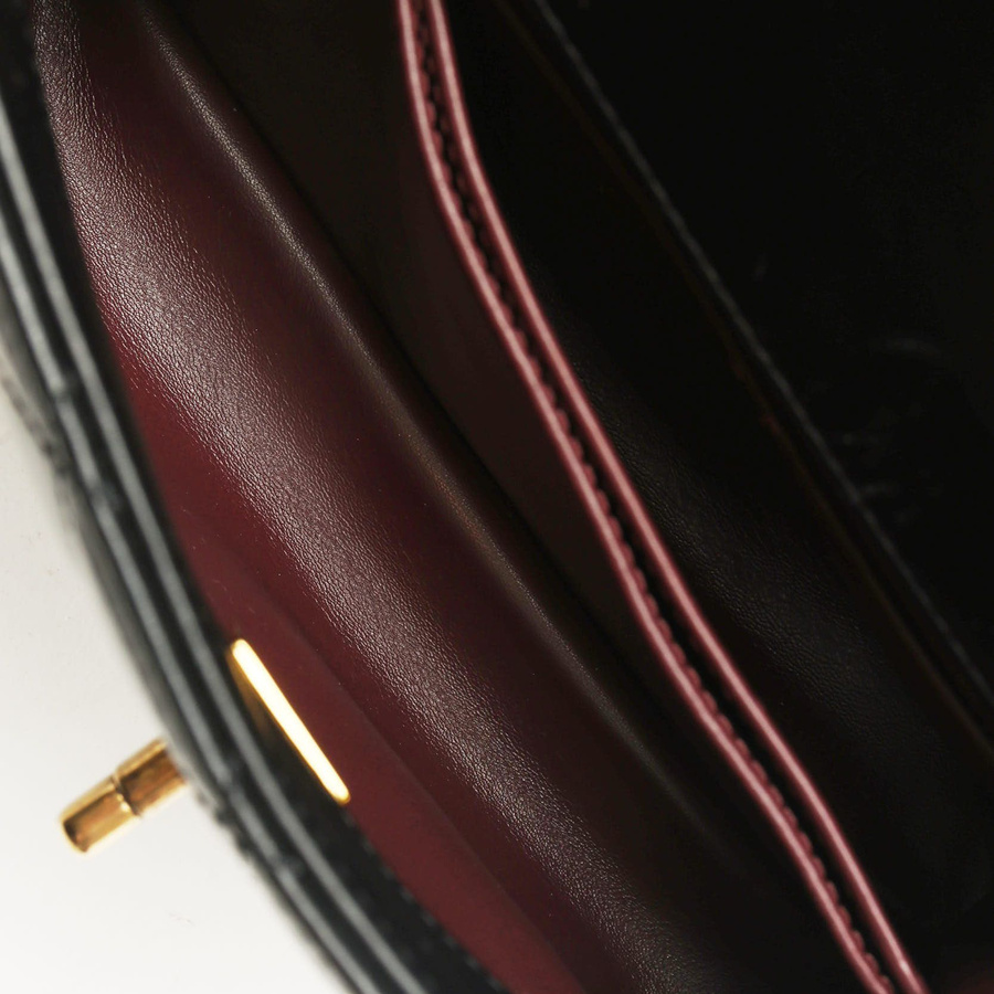 Interior close-up of a Chanel Small Coco Handle Bag, revealing the burgundy leather lining and gold logo stamp.
