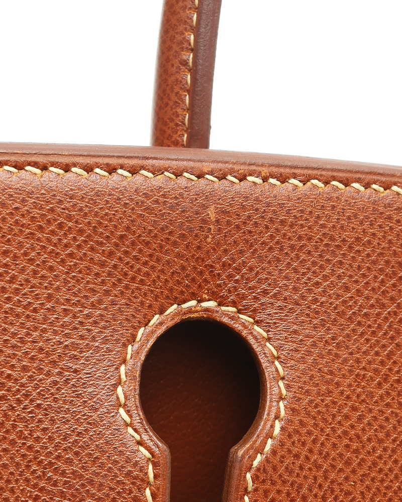 Close-up shot of the Hermès Birkin 30, showing the meticulous stitching on the brown Courchevel leather around the lock opening.