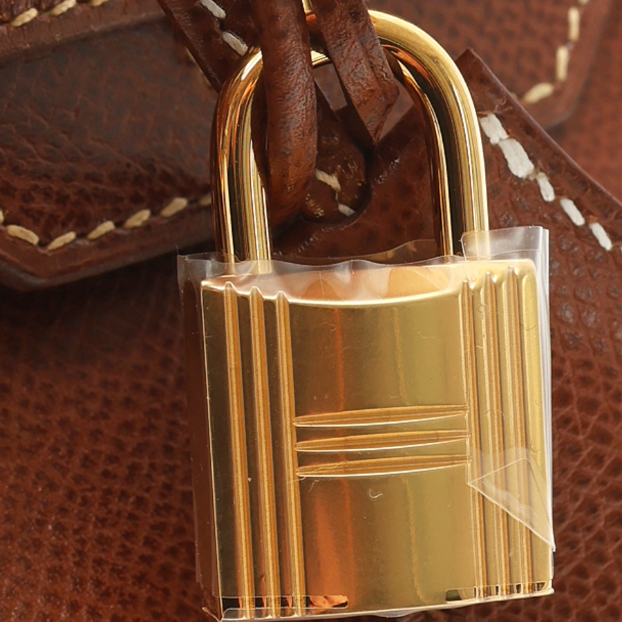 Close-up of the gold-toned padlock on the brown Hermès Birkin 30 Courchevel Bag, highlighting the hardware and leather texture.