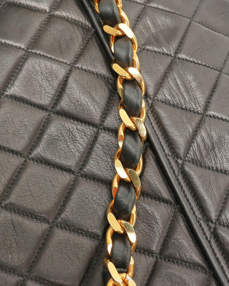 Close-up of the gold-tone chain strap and quilted leather on a Chanel Messenger Flap Bag.