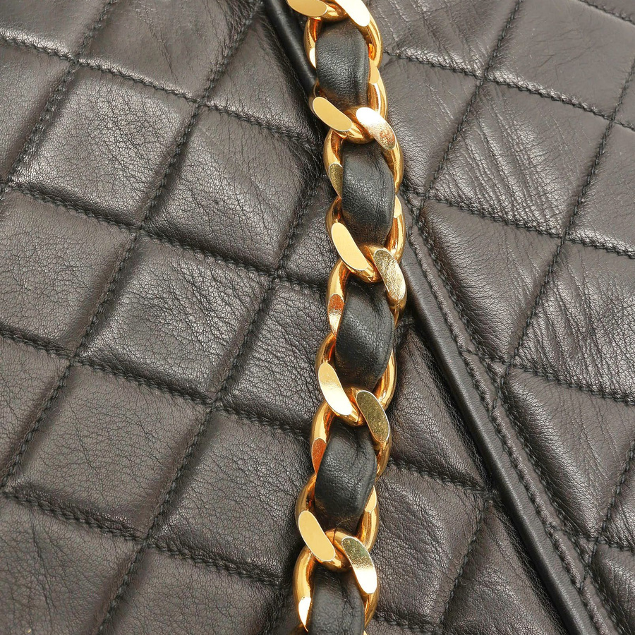 Close-up of the gold-tone chain strap and quilted leather on a Chanel Messenger Flap Bag.
