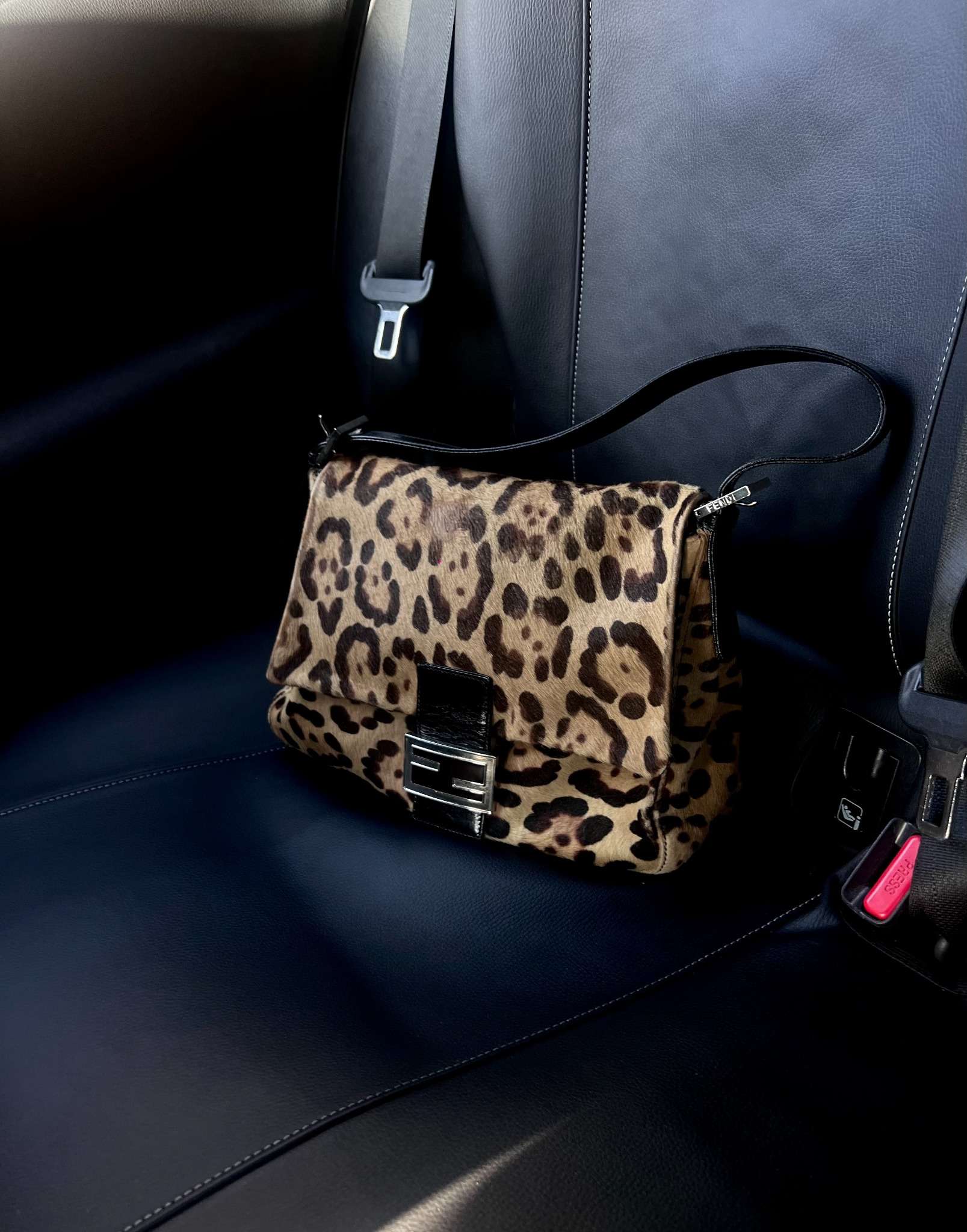 Fendi-väska med leopardmönster på svart bilsäte.