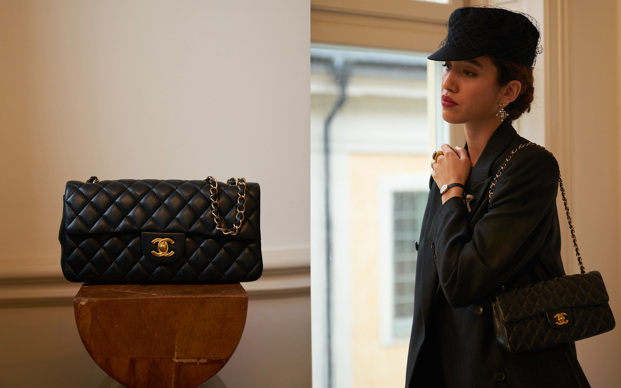 A person dressed in an elegant black outfit and veiled hat, accessorized with statement earrings and brooches. In the first view, they smile while holding a quilted black handbag with gold hardware. In the second view, they stand by a window, reaching toward the handbag resting on a stack of books.