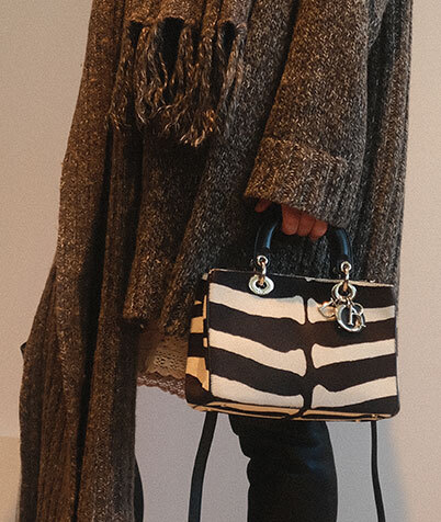 Leopard-print Fendi bag with black shoulder strap lying on a black leather car seat.